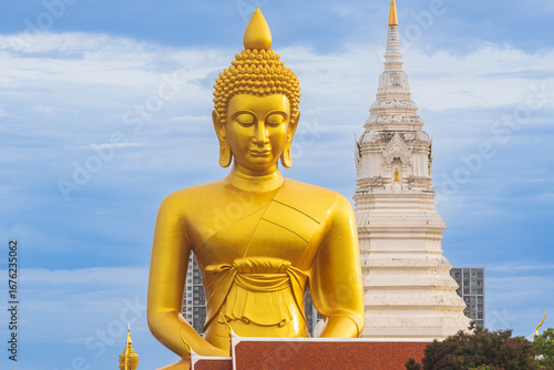 A large seated Buddha or Buddha Dhammakaya Dhepmongkol at Paknam Phasi Charoen temple on a blue sky day.