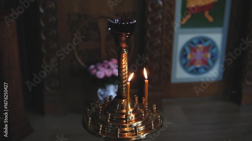 Lit golden candelabra with burning candles in a dimly lit church interior