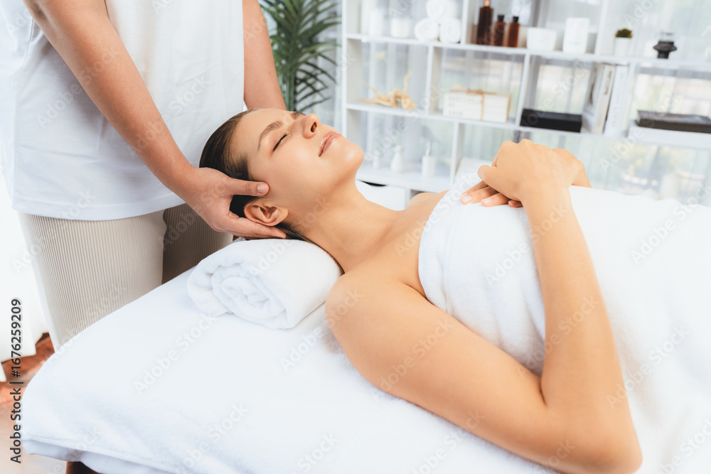 Fototapeta premium Caucasian woman enjoying relaxing anti-stress head massage and pampering facial beauty skin recreation leisure in dayspa modern light ambient at luxury resort or hotel spa salon. Quiescent