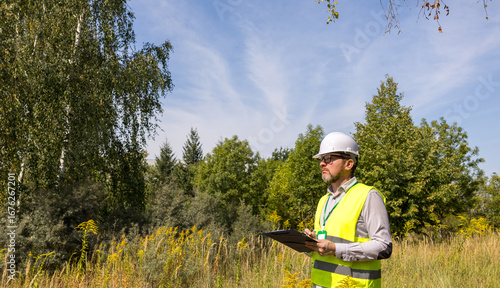 Male forestry inspector studying the condition of trees in the forest. Work Ecologist. Eco control. Conducting environmental monitoring.	
