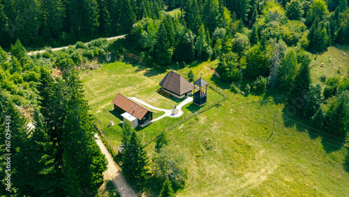 Fotografie Wooden Orthodox church with bell tower and memorial in a mountain village surrou