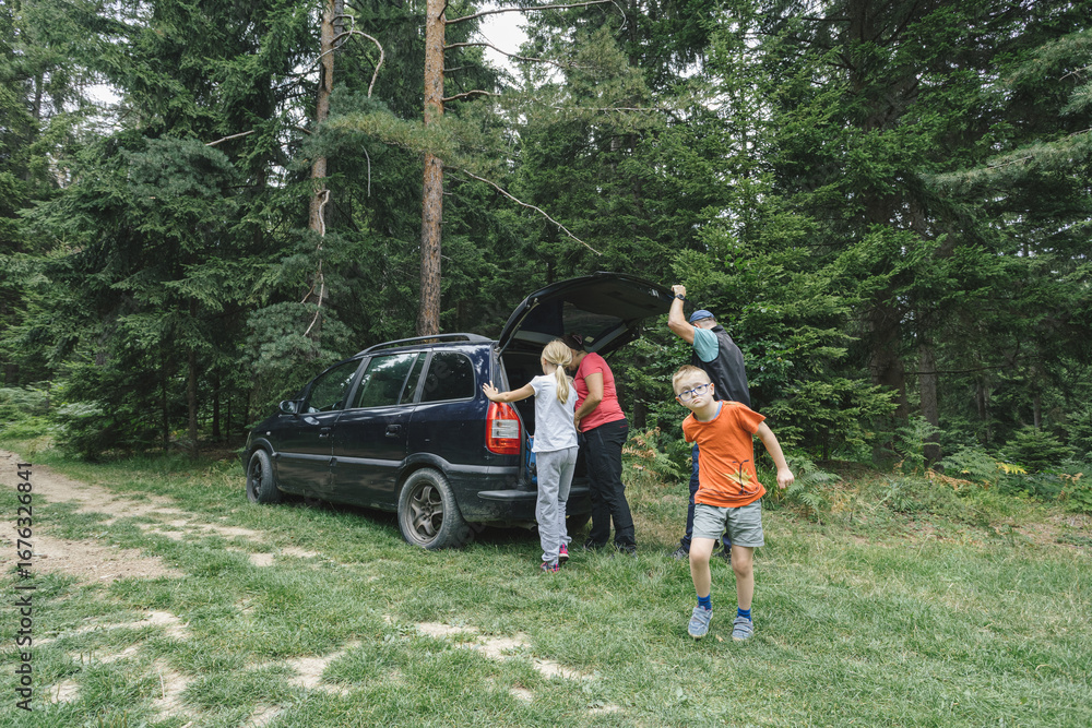 Fototapeta premium Family preparing for hike in the woodlands. Father and son, mom and daughter. Family with child with disability enjoying outdoor adventure in nature.