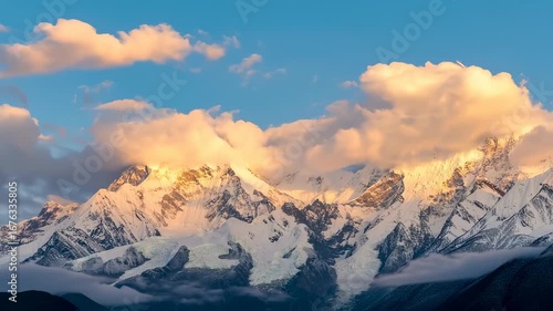 Golden Hour Glow on Majestic Snow-Capped Mountain Peaks with Dramatic Clouds