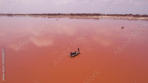 SENEGAL - 7.14.2025 - Amazing aerial footage circling all the way around a man rowing a boat on Dakar, Senegal's Pink Lake.