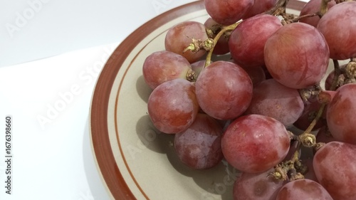 red grapes on a plate with a white background