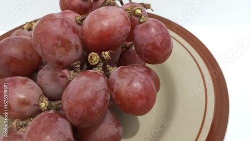 red grapes on a plate with a white background