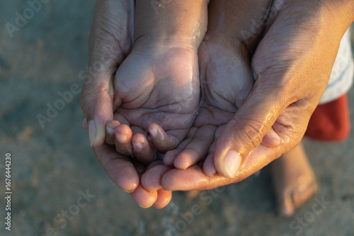 Papier peint Close-up of an adult holding a child’s cupped hands together with water, symbolizing care, love, protection, and bonding