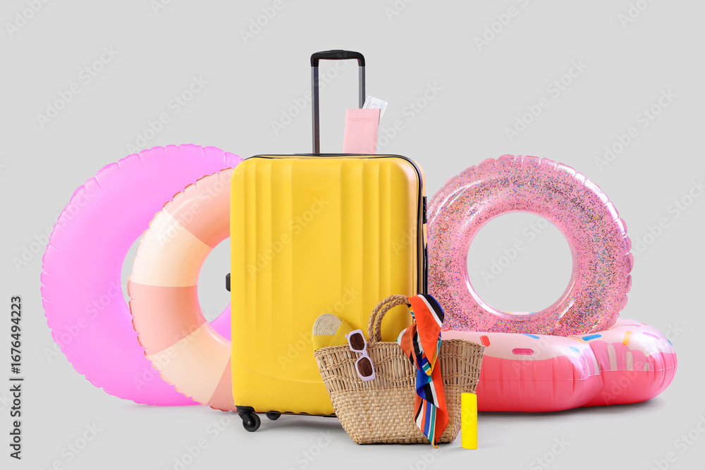 Obraz premium Suitcase, inflatable rings and beach accessories on white background