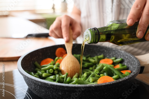 Tableau sur toile Woman with olive oil frying tasty vegetables in kitchen, closeup