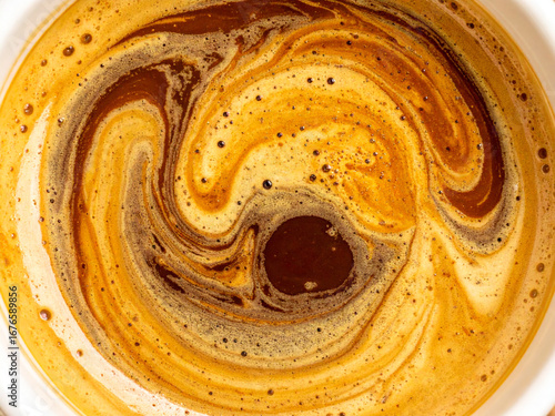 Extreme close-up of swirling espresso crema with marble-like patterns in rich golden brown tones, abstract textured coffee surface, macro shot with blurred cup edges and artistic detail