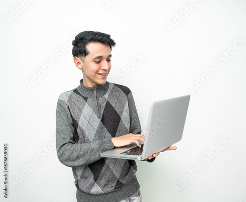 Hombre joven feliz mientras usa una laptop en un fondo blanco aislado