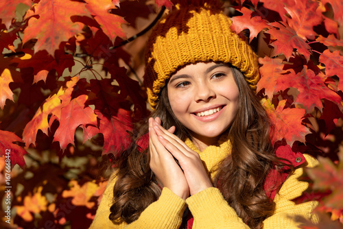 Autumn kid girl face on fall leaf background. Autumn child teenager girl 12, 13, 14 years old portrait. happy kid in hat standing at autumn leaves. fall season