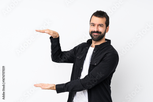 Young man with beard over isolated white background holding copyspace to insert an ad