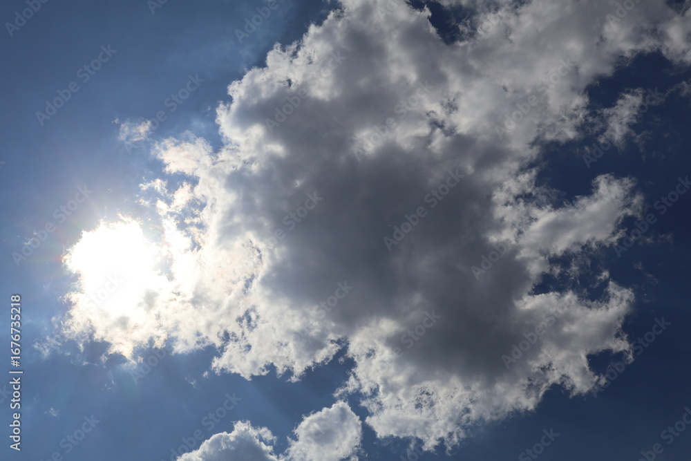 Obraz premium Sun shining through clouds on beautiful blue sky