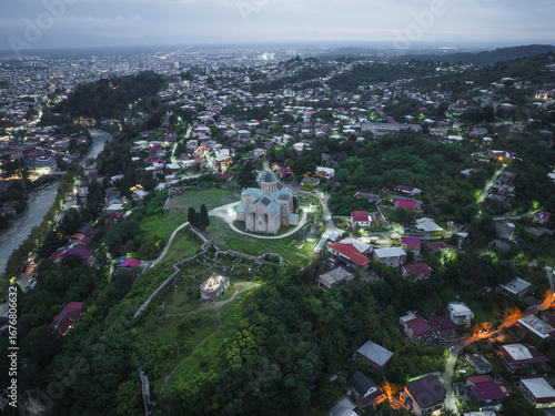 Aerial view of Bagrati Cathedral standing majestically atop Ukimerioni Hill, overlooking the Rioni River winding through the city, Kutaisi, Imereti, Georgia.