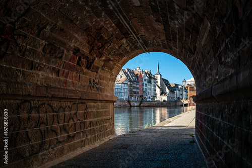 View through a pedestrian tunnel of the river and old town of the city of Strasbourg in France