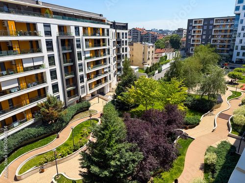 Modern apartment complex with landscaped courtyard, greenery and walking paths viewed from above. Architecture, housing and urban lifestyle highlighting residential design, community and green
