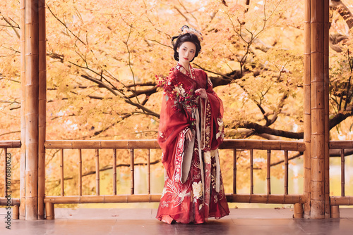 Woman in a traditional red hanfu holding flowers in a serene outdoor setting.