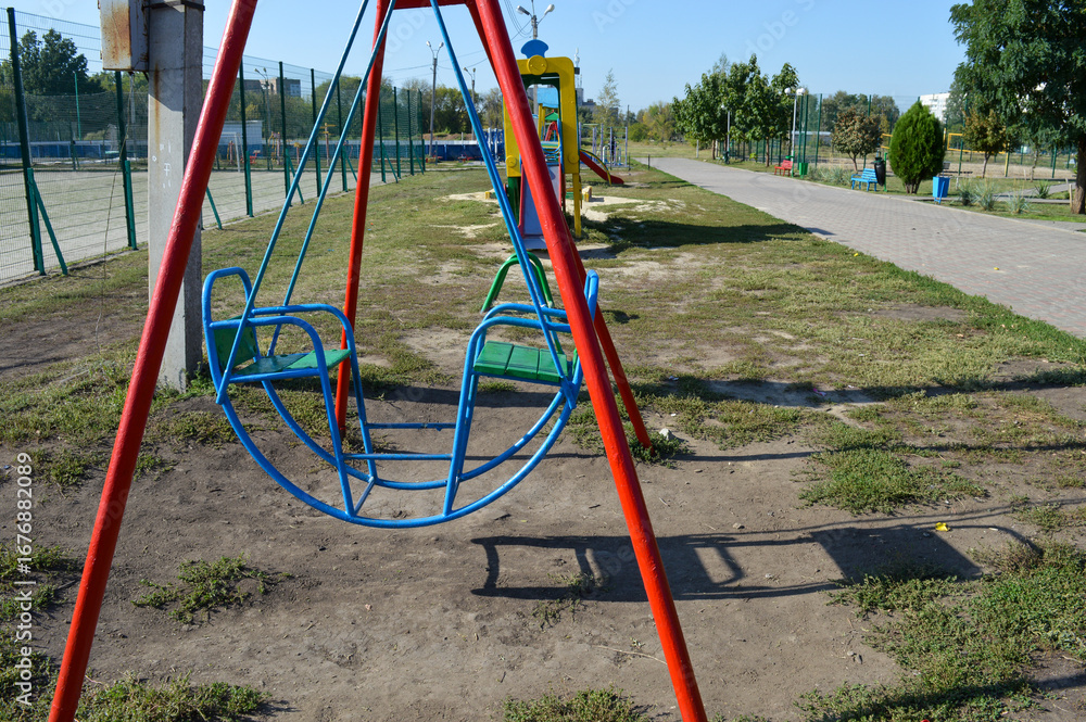 Fototapeta premium colorful metal swing set in a public park, playground equipment for children, outdoor recreation and leisure area