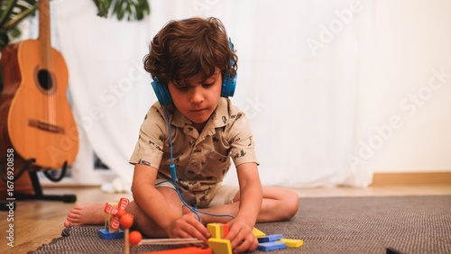 Fotografía Young child playing with building blocks while listening to music on headphones
