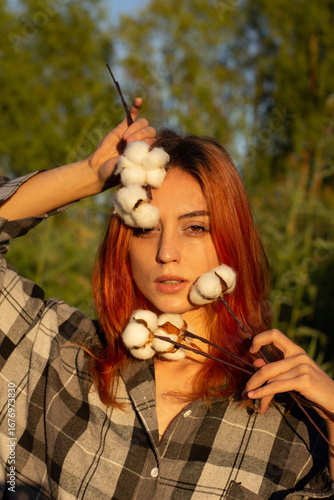 close-up portrait. red-haired girl with cotton flowers. neutral colors