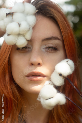close-up portrait. red-haired girl with cotton flowers. neutral colors