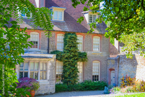 UK, East Grinstead, 24.08.2025: Historic brick manor house with ivy and garden plants