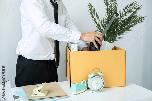 Business man employee packing stationery box and picking up personal belongings into brown cardboard box