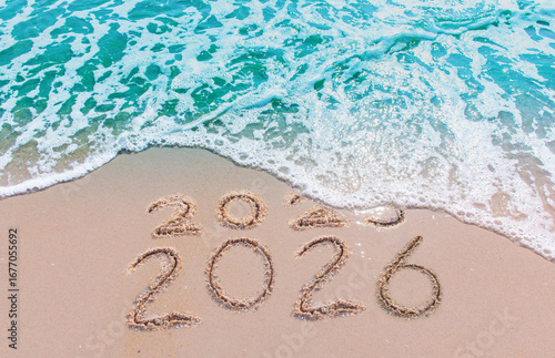 Message Year 2025 replaced by 2026 text written on beach sand background. Good bye 2025 - 2026 happy New Year coming concept.  top view.
