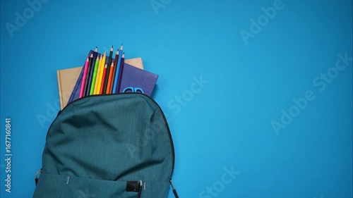 Colorful school supplies moving from school bag on blue background. Back to school concept. Stop motion animation