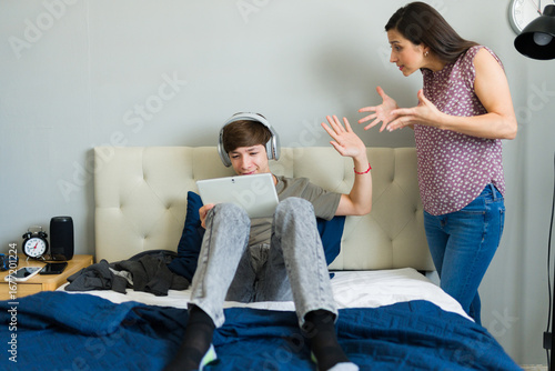 Billede på lærred Teenager ignoring his mother while using a tablet in his bedroom