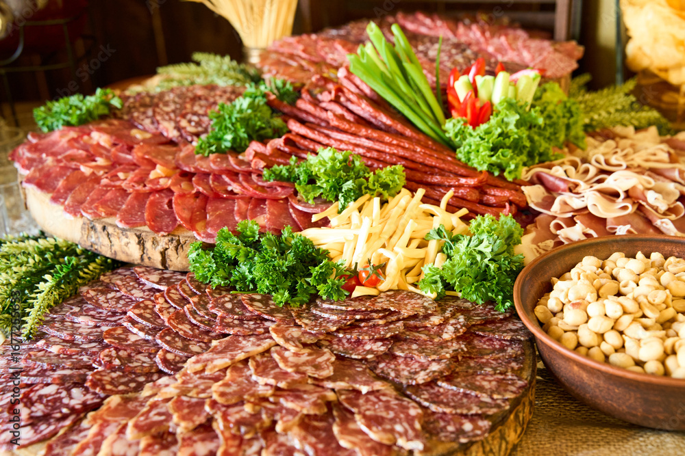 Fototapeta premium Delicious charcuterie spread featuring a variety of meats, cheeses, and fresh garnishes arranged beautifully on wooden boards