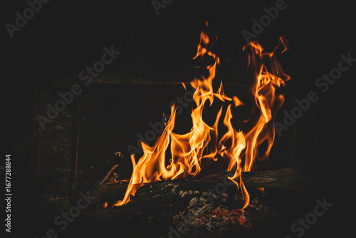 Bright orange flames rising from a wood vine barbecue fire, glowing and crackling with natural warmth