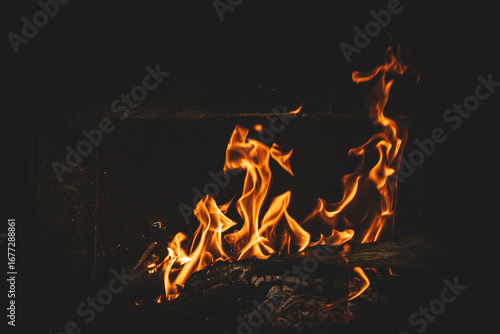 Bright orange flames rising from a wood vine barbecue fire, glowing and crackling with natural warmth