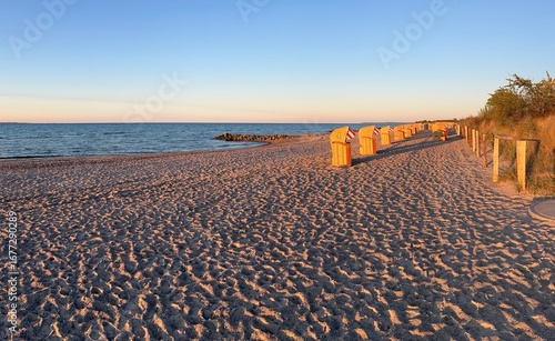 Beach with wicker chairs and sunset light on German coast