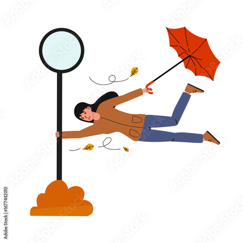 Woman struggles to hold onto umbrella while being blown by strong wind near a signpost in autumn