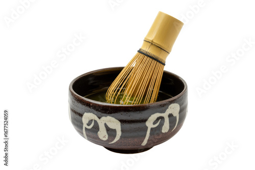 Canvastavla A matcha whisk inside a dark brown bowl with white designs, preparing a vibrant green matcha tea