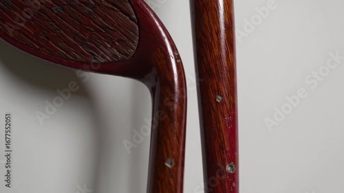 Two vintage wooden golf clubs with signs of wear and aged patina, one with red grip, isolated on white background, symbolizing classic golf equipment
