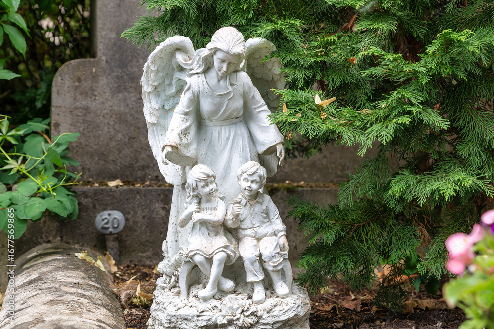 Obraz premium schöner großer Engel hinter zwei Kindern auf dem Friedhof in Würzburg