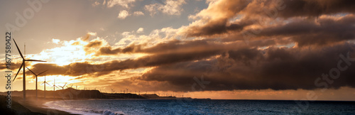 Sunset wind turbines across the coastline with dramatic sky and ocean