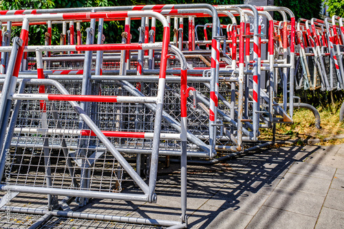 Metal barriers stacked on a city street near an event location in bright sunlight during daytime hours