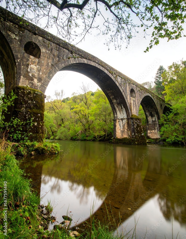 Fototapeta premium Ancient stone arch bridge over a calm river