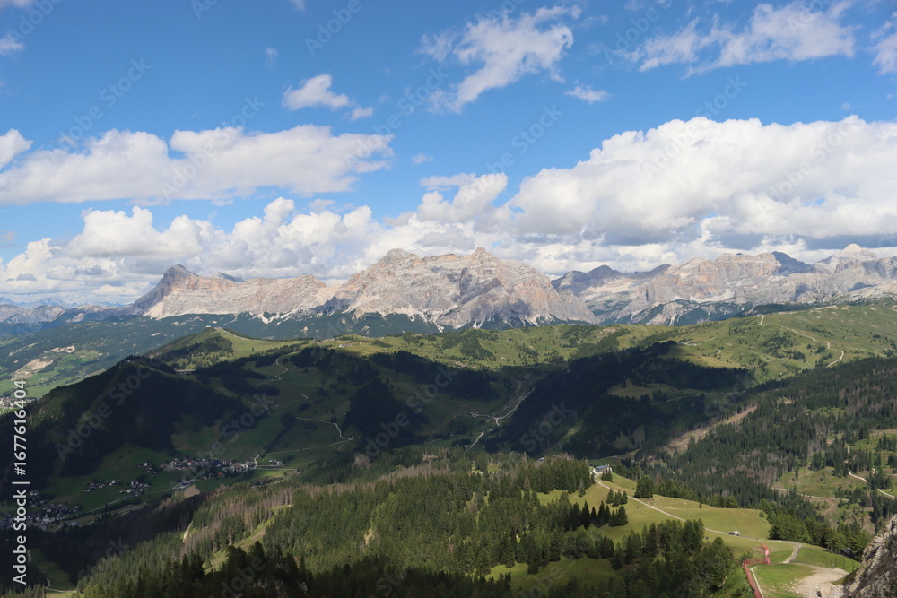 Obraz premium Trentino, Italy - July 29, 2025: Panoramic view of the majestic Piz Boe and the surrounding Dolomite peaks, with lush green valleys and scattered snow, under a clear blue sky. beautiful view to Lake b