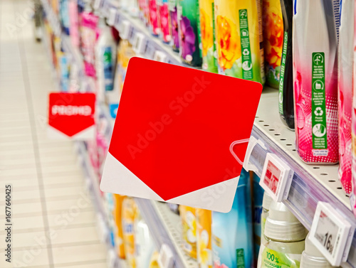 Blank red square shelf label on supermarket aisle fixture for in store promotion, empty price tag signage sign, store shelf, retail products display, copy space, buying selling goods items, no people