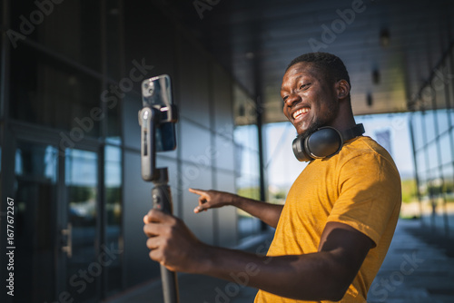 Canvas Print Excited influencer creating content with smart phone gimbal