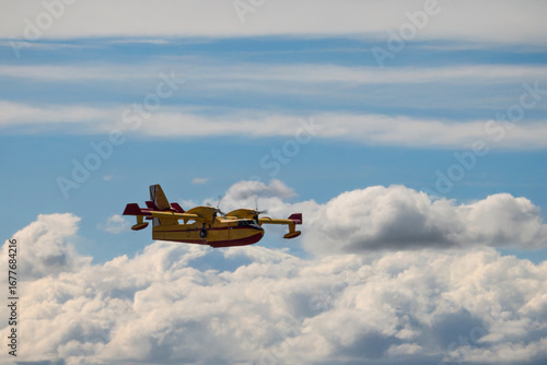 Firefighting aircraft flying over dramatic layered clouds.