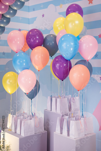 Colorful party balloons with gift bags on pedestals, festive kids birthday decoration