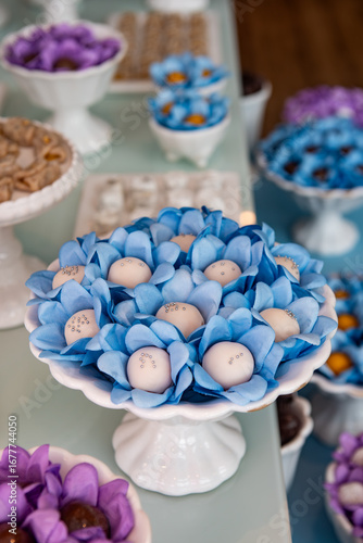 Colorful party candy table with assorted sweets in blue and purple wrappers on elegant white stands, festive decoration for celebration