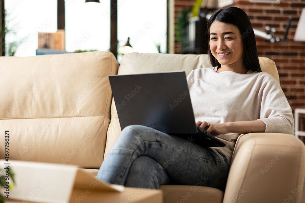 Fototapeta premium Female freelancer researching strategies and reviewing emails while managing tasks remotely. Asian entrepreneur excited after completing financial data and project presentation from home.