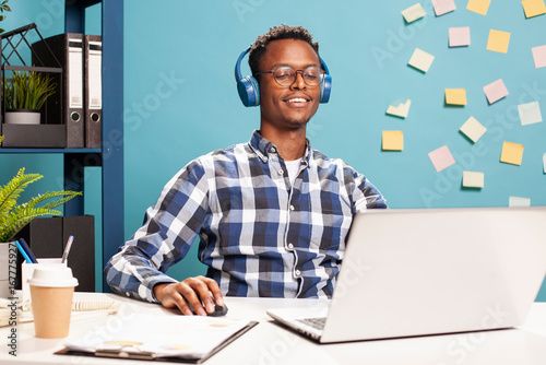 Photos Young businessman with headphones, working on his laptop, brainstorming ideas for startup company